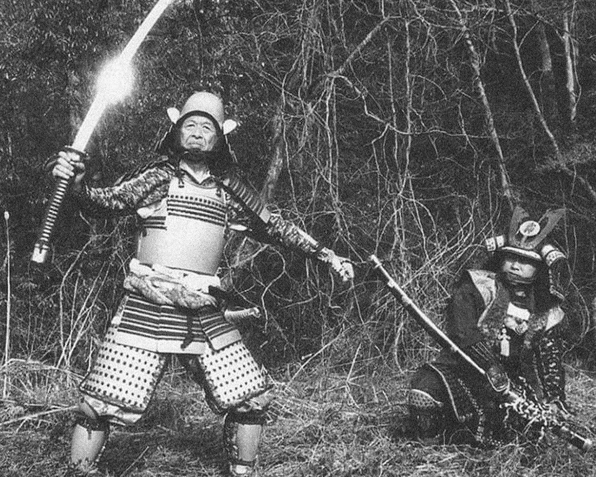 A swordsman in samurai armour raising a katana in a forest