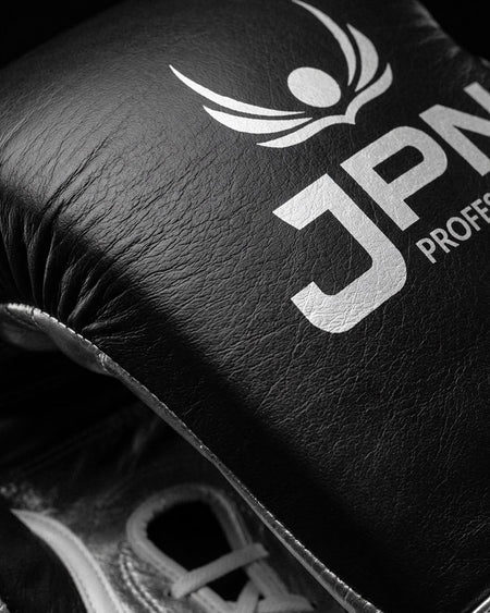Close-up of the silver JPN Professional crest on black glove leather above white laces