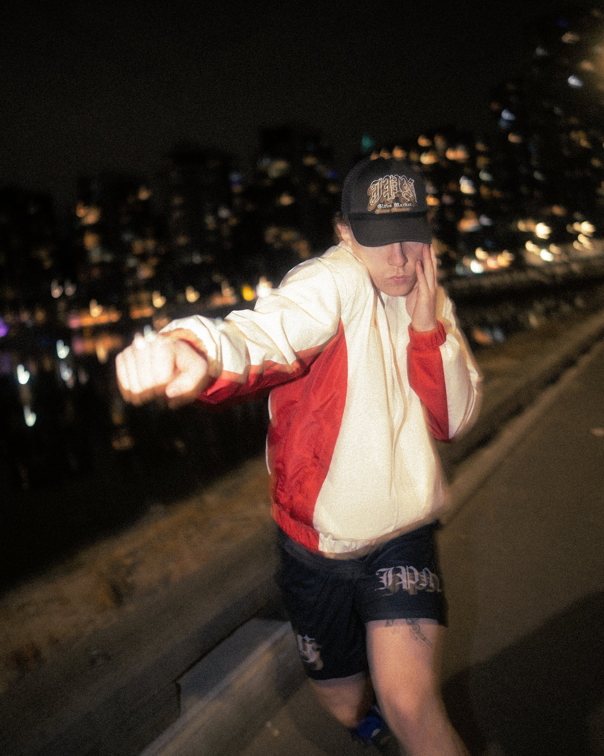 Liam throwing a punch at night in the Team Japan jacket and a JPN cap